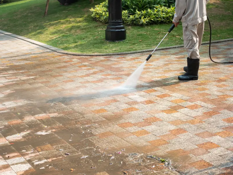APS Window and Gutter and Pressure Washing | Concord NC   APS Pressure Washing technician cleaning a brick driveway in Concord NC with high pressure water to remove dirt stains and debris