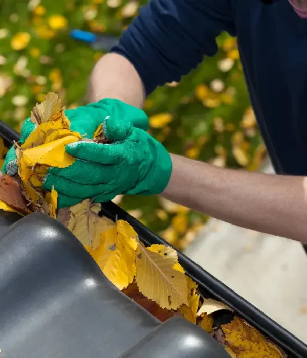 APS Gutter Cleaning technician in Concord, NC removing fall leaves by hand from a residential gutter to prevent clogs and water damage.